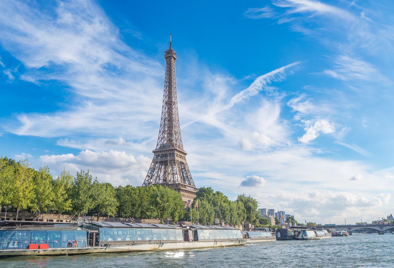 La Tour Eiffel ensoleillée vue depuis un bateau naviguant sur la Seine, lors d'une belle journée d'été de 2013