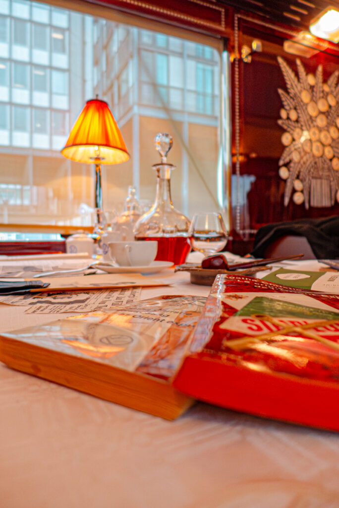 Vue intérieure d'une voiture de l'Orient Express, restaurée et présentée lors de l'exposition 'Il était une fois l'Orient Express' à l'Institut du Monde Arabe à Paris en 2014, montrant une table joliment dressée avec des livres, évoquant l'art de vivre et de voyager caractéristique du train légendaire.