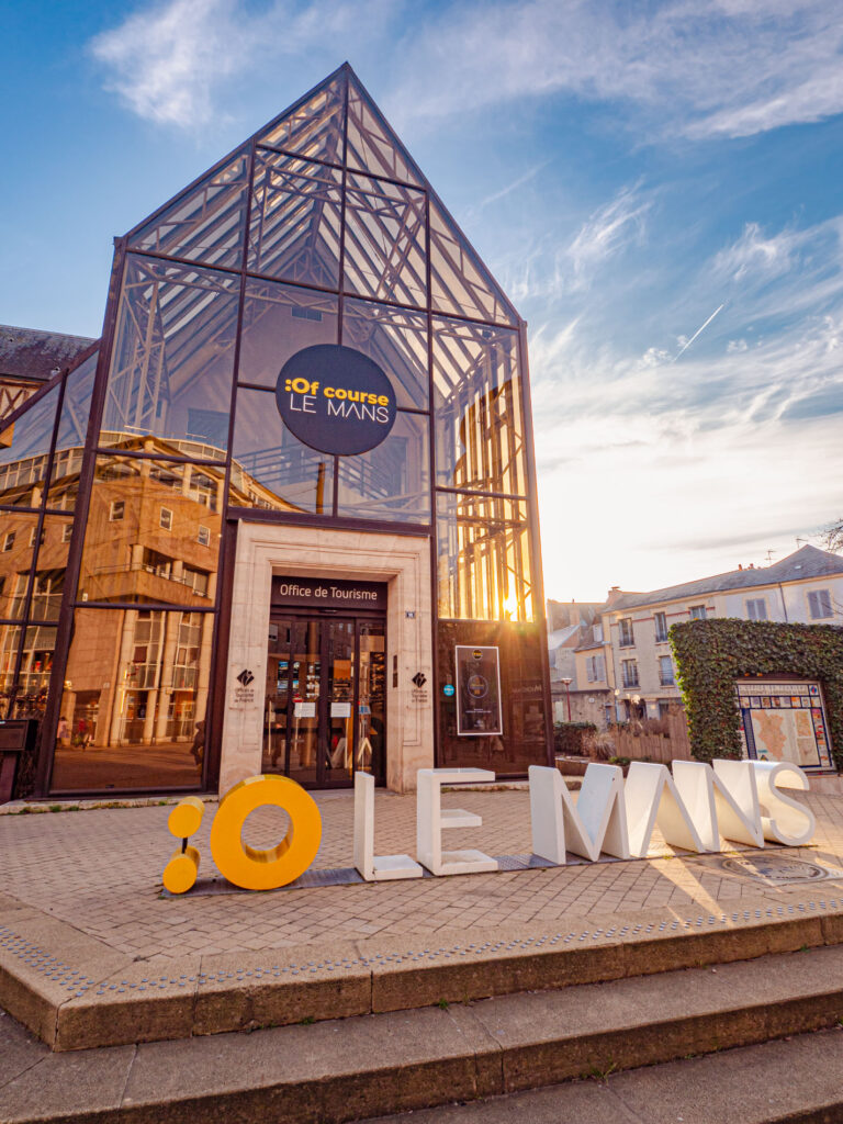 Cette image présente l'Office de tourisme du Mans, pris à l'heure magique du crépuscule. Le bâtiment de l'Office de tourisme, éclairé par des lumières chaleureuses, se détache contre le ciel aux nuances profondes de bleu. L'atmosphère est paisible et invitant, le bâtiment servant de point lumineux dans la scène du soir qui se déroule. C'est un guide pour les voyageurs et les résidents, promettant de nouvelles aventures et de nouvelles découvertes au sein de cette ville historique. La photographie capture l'ambiance tranquille et la beauté sereine de ce moment du soir.