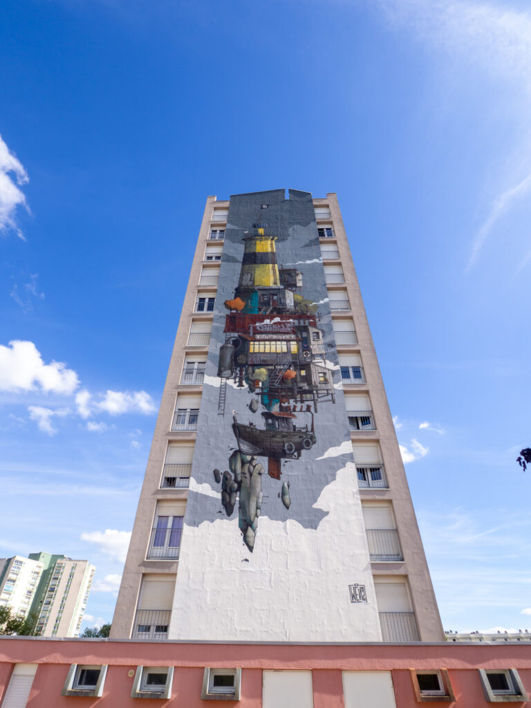 Une photo capturant une fresque colorée et complexe réalisée par l'artiste Wen 2 sur un immeuble résidentiel dans le quartier des Sablons, au Mans, en Sarthe, France. Cette œuvre d'art, qui a été créée en parallèle du festival de street-art Plein Champ, transforme le bâtiment en une toile urbaine impressionnante. La fresque est pleine de formes géométriques, de couleurs vives et de détails intricats qui s'entrelacent pour créer une représentation visuellement stimulante. L'artiste a su intégrer harmonieusement son travail à l'architecture existante de l'immeuble, créant ainsi une pièce d'art public qui ajoute de la vitalité et du dynamisme à l'environnement urbain. Les passants peuvent être vus en bas, illustrant l'échelle massive de cette œuvre d'art.